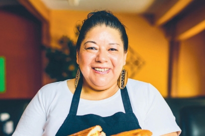 Maria Medina shows off her Torta Chilanga gigante cubana style, which is a giant sandwich with leg meat, chorizo, hot dogs, eggs, ham, and milanesa (a flattened steak that has been breaded and fried), all topped with cheese