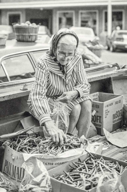 old woman sells green beans at farmers market