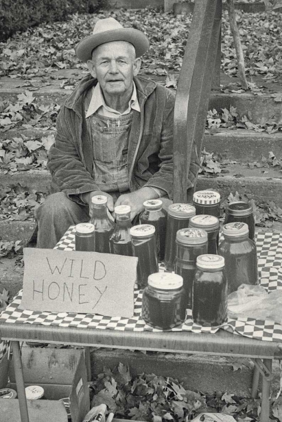 man sells wild honey on table outside